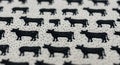 Black cow silhouettes are embroidered on a textured, light beige fabric, forming a Royalty Free Stock Photo