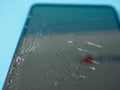 Black crashed smartphone with broken screen and body on a blue table in service.