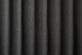 Black crepe paper background with vertical waves and a small pattern.