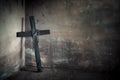 Black cross against wall with hanging steel chain and gun. Halloween day party festival celebration. Ancient sign of religion. Da