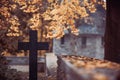 Black cross in the cemetery with mausoleum