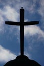 a cross on a hill against a sky background with white clouds Royalty Free Stock Photo