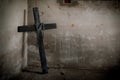 Black crucifix against wall with hanging steel chain and gun. Halloween day party festival celebration. Ancient sign of religion