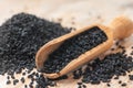 Black cumin seeds and wooden scoop, texture background Royalty Free Stock Photo