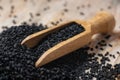 Black cumin seeds and wooden scoop  texture background Royalty Free Stock Photo