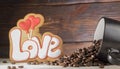 Black cup with coffee seeds, cookies in the shape of the word love and two red hearts, on a wooden background Royalty Free Stock Photo