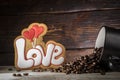 Black cup with coffee seeds, cookies in the shape of the word love and two red hearts, on a wooden background Royalty Free Stock Photo