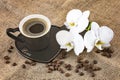 Black cup of coffee and white orchid flowers on a dark background. Coffee beans and burlap as decor. Royalty Free Stock Photo