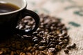 Black cup with handle, on a coffee sack with roasted beans around