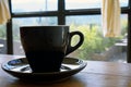 Black cup with steaming hot coffee on the wooden table with blurred green garden background Royalty Free Stock Photo