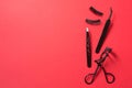 Black curler, false eyelashes and tweezers on red background, copy space Royalty Free Stock Photo