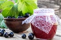 Black currant jam on the background of old boards near the green leaves and berries of currants. Natural currant jam Royalty Free Stock Photo