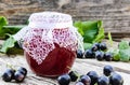 Black currant jam on the background of old boards near the green leaves and berries of currants. Natural currant jam Royalty Free Stock Photo