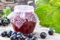 Black currant jam on the background of old boards near the green leaves and berries of currants. Natural currant jam Royalty Free Stock Photo