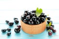 Black currant with leaf in wooden bowl on blue wooden table Royalty Free Stock Photo