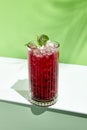 Black currant lemonade drink over green background. White table with sunlight and palm leaf hard shadow. Summer, tropical and Royalty Free Stock Photo