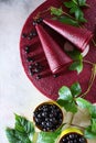 Black currant pastila on a light background. The sweetness is curled up in a cone. Nearby is a branch with green leaves. Black Royalty Free Stock Photo