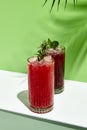Black currant and raspberry lemonade drink over green background. White table with sunlight and palm leaf hard shadow. Summer, Royalty Free Stock Photo