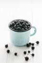 Black currant in tea cup on a white wooden table Royalty Free Stock Photo