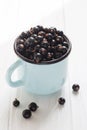 Black currant in tea cup on a white wooden table Royalty Free Stock Photo