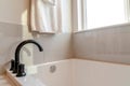 Black curved faucet and built in bathtub inside bathroom with white tile wall Royalty Free Stock Photo