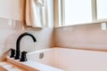 Black curved faucet on the rim of built in rectangular bathtub inside bathroom Royalty Free Stock Photo