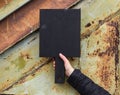 Black cutting board held in hand on corroded metal textured back Royalty Free Stock Photo