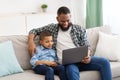 Black Daddy And Son Watching Movie On Laptop At Home