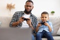 Black Daddy And Son Playing Videogame Together Sitting At Home