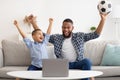 Black Daddy And Son Watching Sport On Laptop At Home