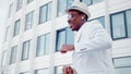 Black dance performer in wireless headphones and glasses moves on square among megalopolis highrise buildings