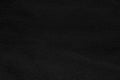 Black dark one-color solid rough textured fabric, textile with folds. Monochromatic template, backdrop Royalty Free Stock Photo