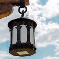 Black decorative antique forged metal lantern on an iron ring. A Royalty Free Stock Photo