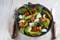 Black deep bowl of Greek salad, fork and knife on a white background. Royalty Free Stock Photo