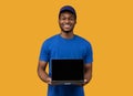 Black delivery guy holding laptop with blank screen for mockup