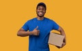 Black delivery man holding cardboard box showing thumb up Royalty Free Stock Photo