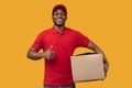 Black delivery man holding cardboard box showing thumb up Royalty Free Stock Photo