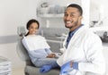 Black dentist doctor and patient in chair smiling at camera