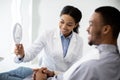 Black Dentist Lady Holding Mirror, Showing Teeth Treatment Result To Patient