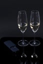 Black device and 2 glasses with champagne on a black background.