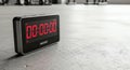 Black digital timer with red LED display showing 00:00:00 on a concrete floor, ready for a workout or countdown Royalty Free Stock Photo