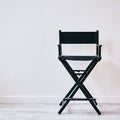 Black director`s chair against a white wall