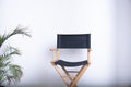 Black director's chair against a white wall Make-up chair Green plant background