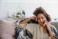 Black displeased woman talking on mobile phone while sitting on sofa Royalty Free Stock Photo