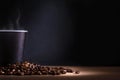 Black disposable cup of coffee with smoke and scattered coffee beans on dark background