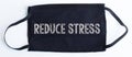 Black disposable protective mask with reduce stress text on black background