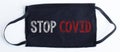 Black disposable protective mask with STOP COVID text on black background