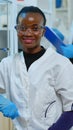 Black doctor woman smiling at camera sitting in scientific lab