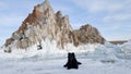 Black dog lies on the snow-covered ice of lake Baikal at Cape Burhan and Shamanka rocks Royalty Free Stock Photo