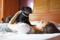 Black dog on top of a woman in bed. Dog in bed concept. Pampering and petting the dog. Royalty Free Stock Photo